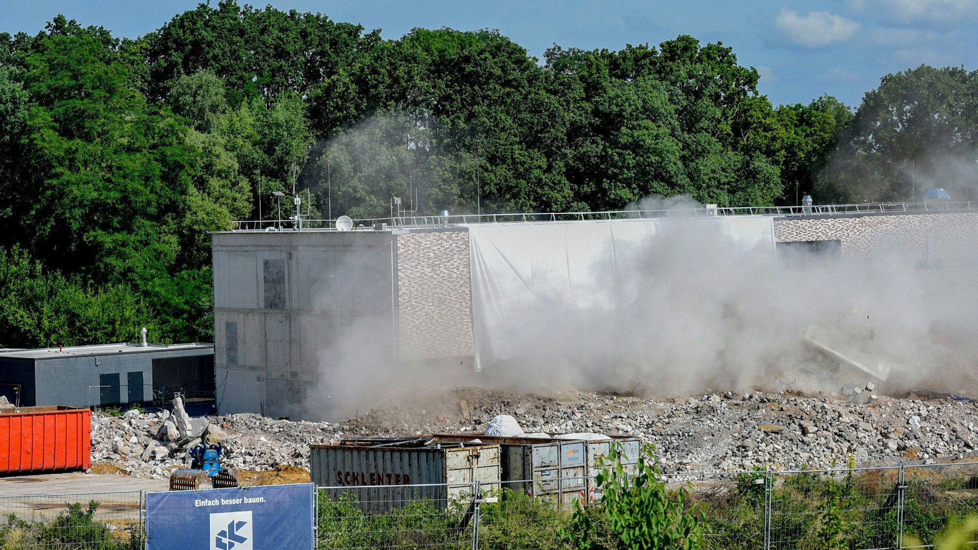 Das Foto zeigt Staub über Trümmern vor einem Neubau.