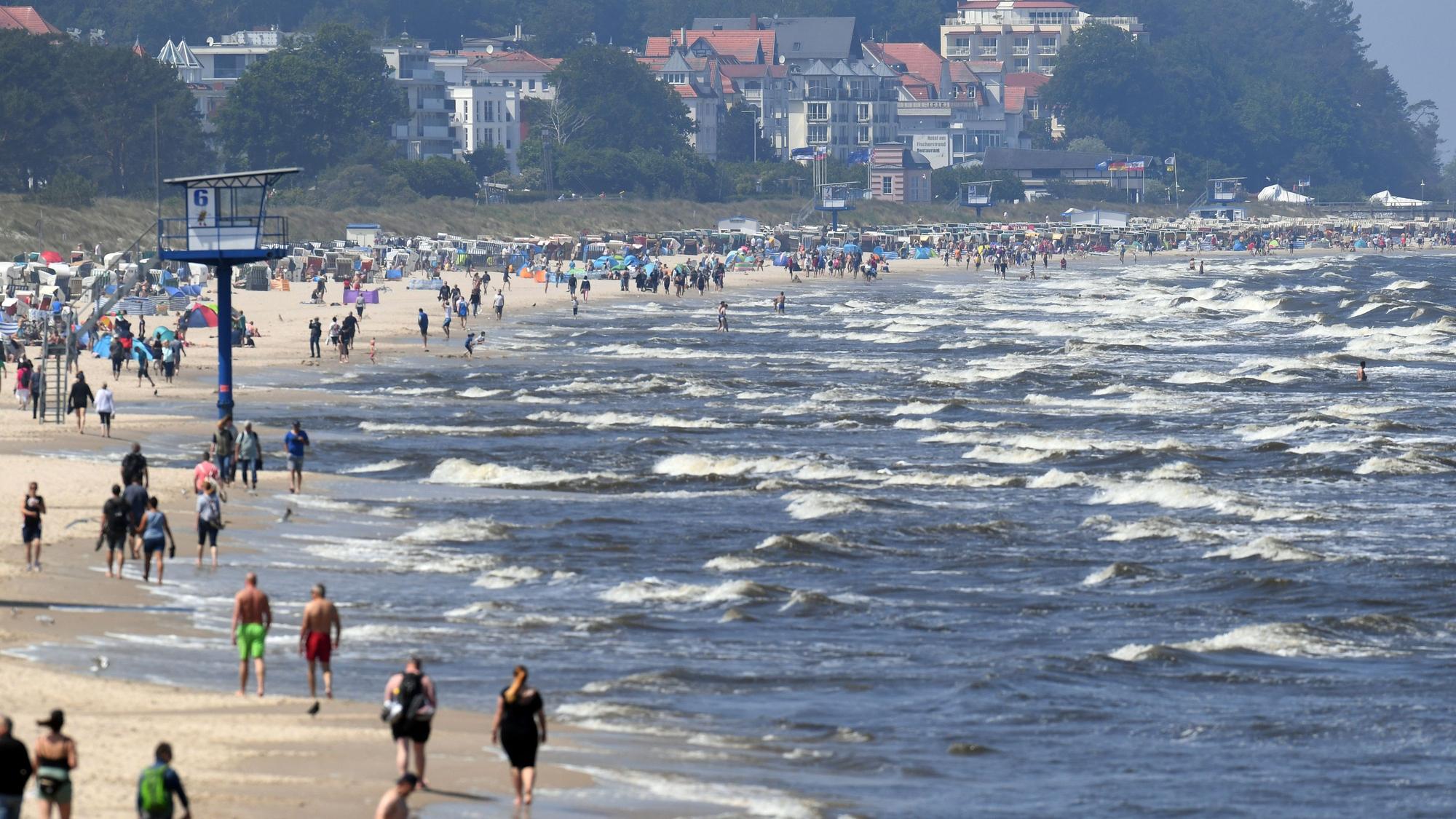 ARCHIV - 13.06.2020, Mecklenburg-Vorpommern, Heringsdorf: Touristen spazieren am Strand an der Ostsee auf der Insel Usedom entlang. Millionen Urlauber in Deutschland fahren jedes Jahr ans Meer. Doch Küste ist nicht gleich Küste. Wer es mild und romantisch mag, bevorzugt die Ostsee. Wilder und rauer geht es hingegen an der Nordsee zu. (zu dpa "Nordsee vs. Ostsee - Was Urlauber an die Küsten zieht") Foto: Stefan Sauer/dpa-Zentralbild/dpa +++ dpa-Bildfunk +++