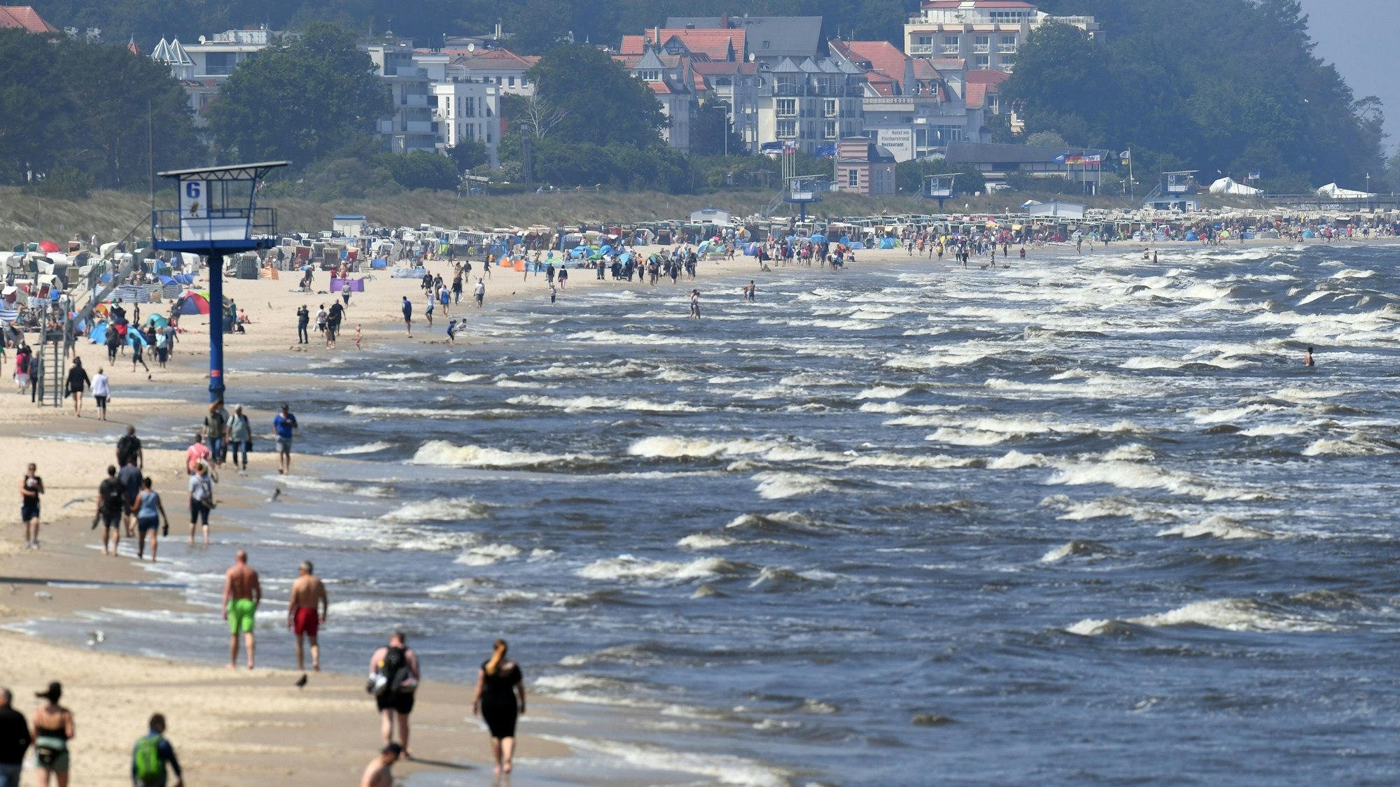 ARCHIV - 13.06.2020, Mecklenburg-Vorpommern, Heringsdorf: Touristen spazieren am Strand an der Ostsee auf der Insel Usedom entlang. Millionen Urlauber in Deutschland fahren jedes Jahr ans Meer. Doch Küste ist nicht gleich Küste. Wer es mild und romantisch mag, bevorzugt die Ostsee. Wilder und rauer geht es hingegen an der Nordsee zu. (zu dpa "Nordsee vs. Ostsee - Was Urlauber an die Küsten zieht") Foto: Stefan Sauer/dpa-Zentralbild/dpa +++ dpa-Bildfunk +++