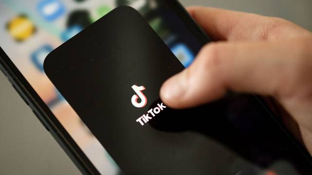 Ein Teenager tippt auf das TikTok-Logo auf einem Smartphone.