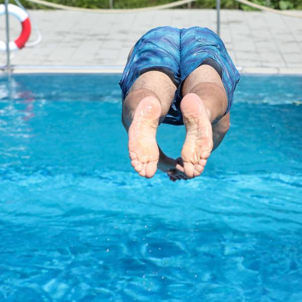 Ein Mann springt von einem Sprungbrett kopfüber ins Wasser.