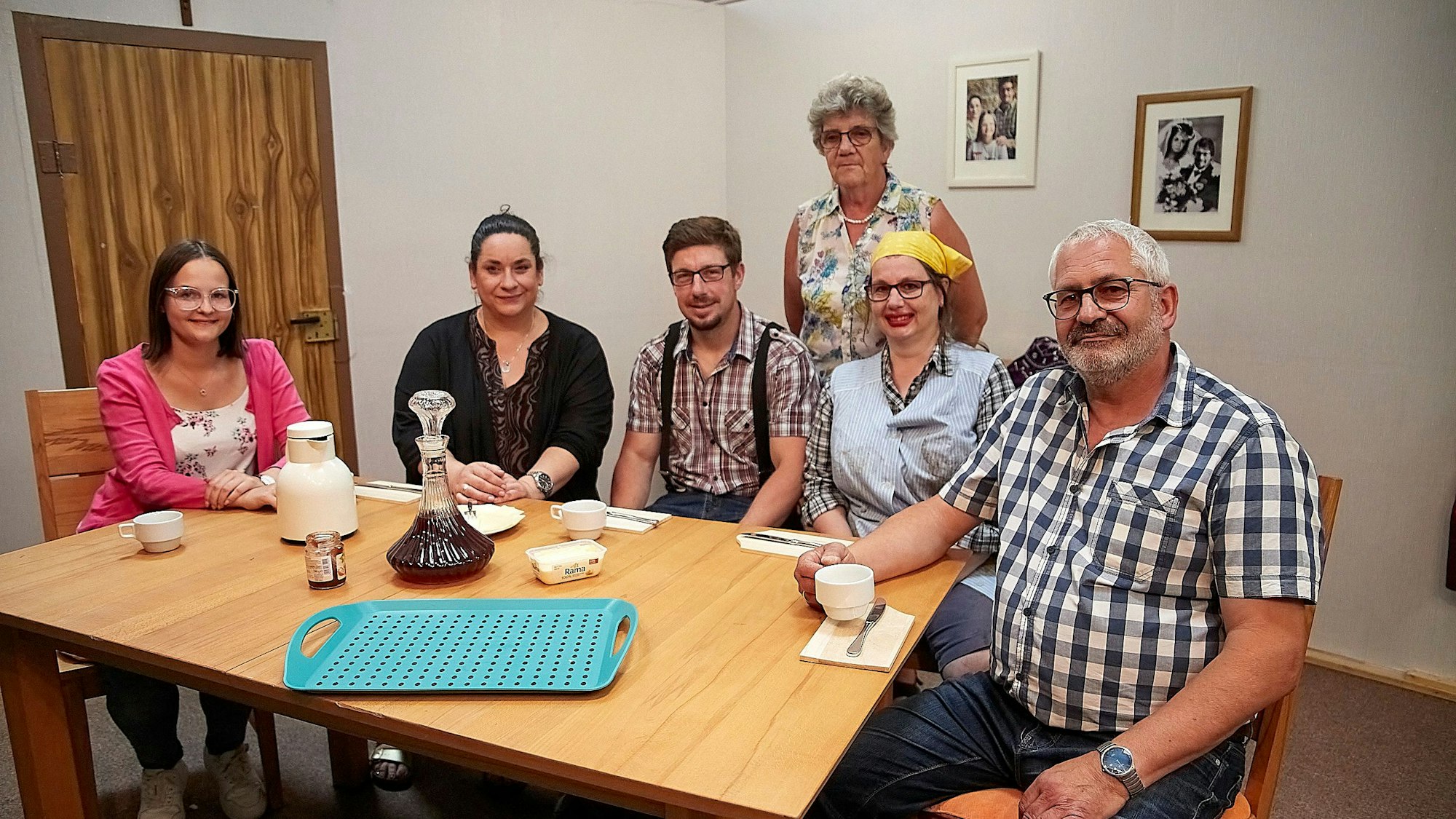 Mehrere Männer und Frauen, Darsteller eines Theatervereins, sitzen um einen Tisch herum.