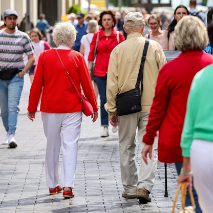 Ein älteres Paar in der Leipziger Fußgängerzone ist von hinten zu sehen. Der Mann nutzt einen Gehstock.