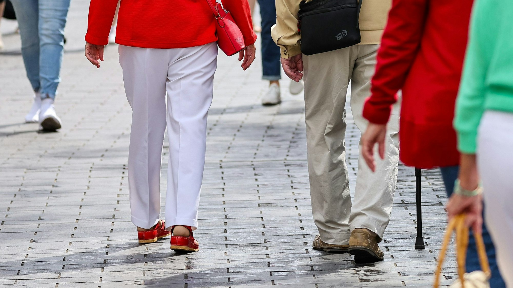 Ein älteres Paar in der Leipziger Fußgängerzone ist von hinten zu sehen. Der Mann nutzt einen Gehstock.