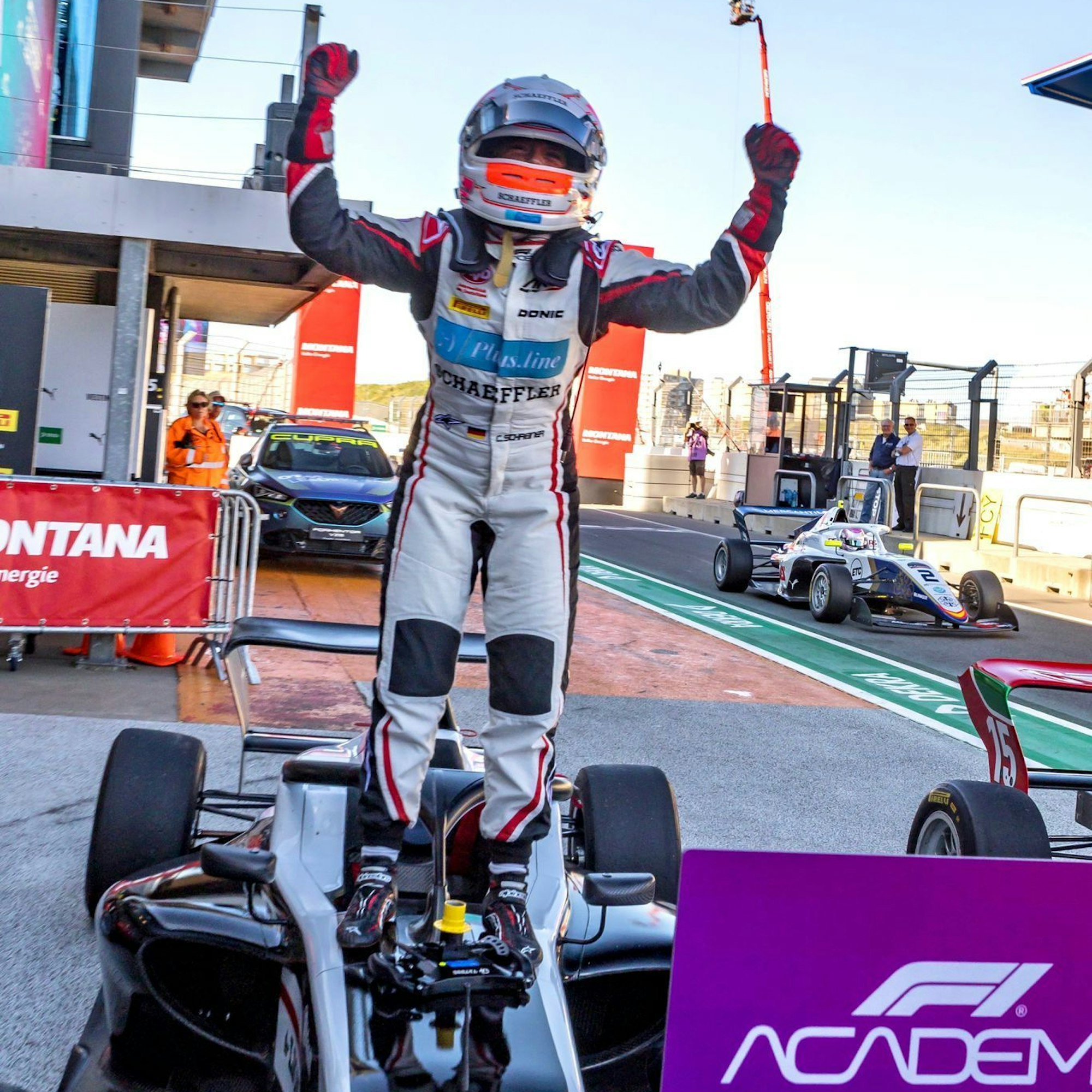 Rennfahrerin Carrie Schreiner steht jubeln auf ihrem Rennauto.