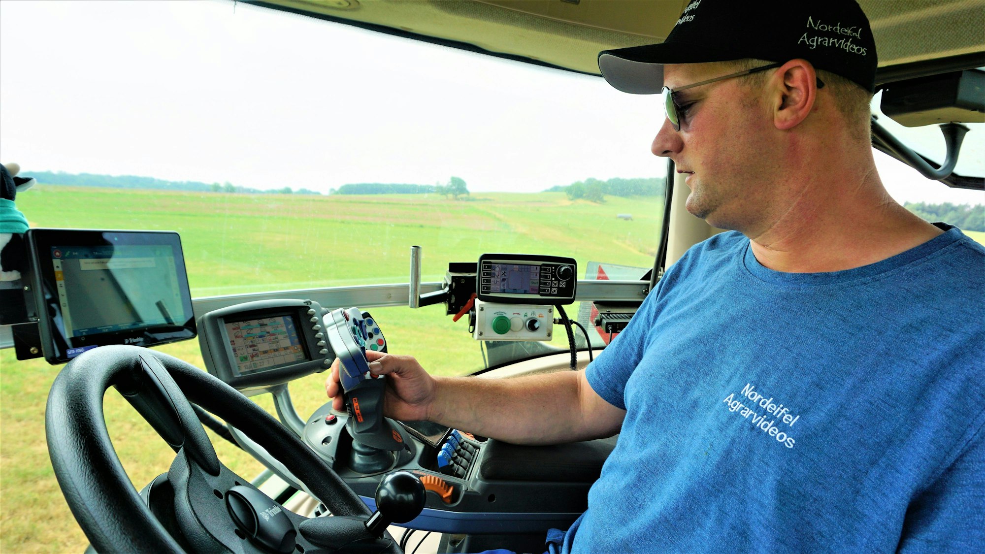 Sebastian Bützler sitzt in seinem Traktor und ist umgeben von Bildschirmen und Controllern.