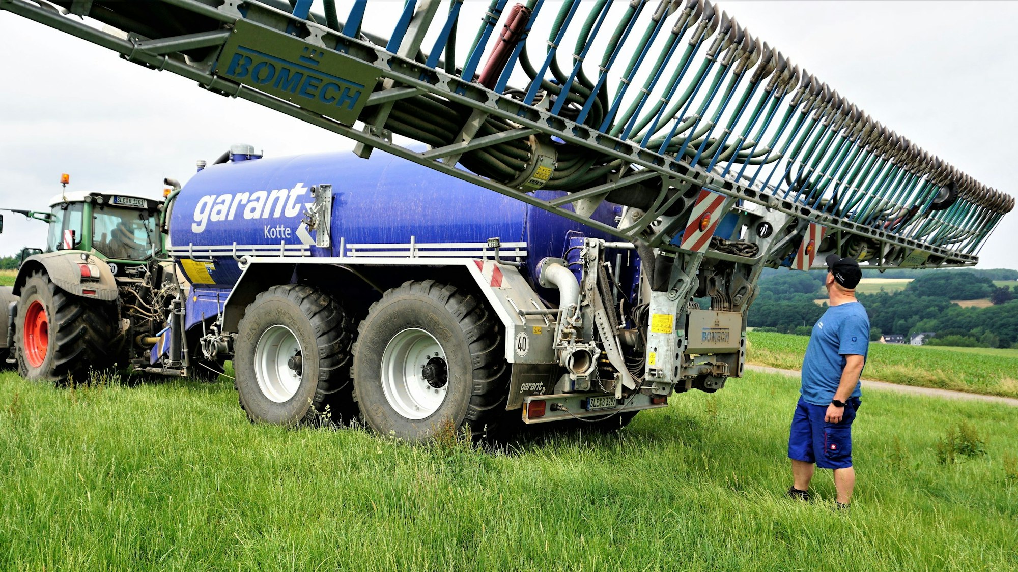 Sebastian Bützler steht hinter schwerem landwirtschaftlichen Gerät.