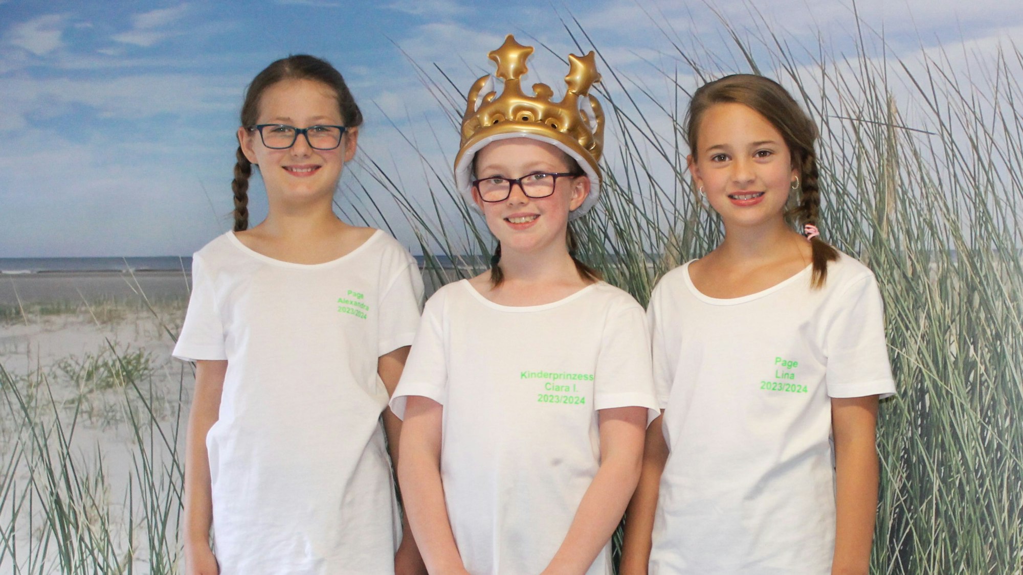 Das Foto zeigt drei Mädchen im weißen T-Shirts, eines davon mit einer Krone auf dem Kopf.