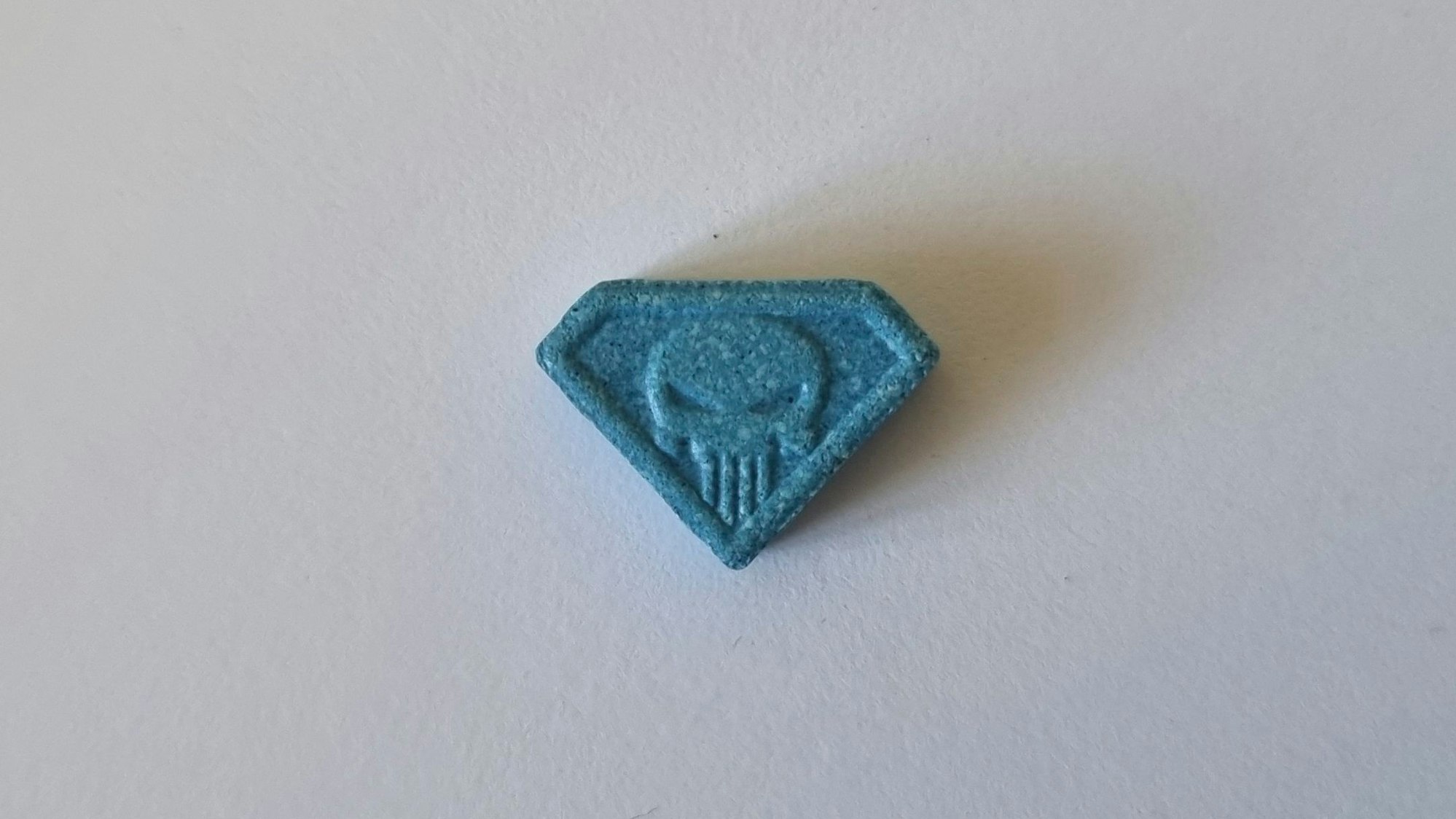 Die blaue Pille „Blue Punisher“ liegt auf dem Tisch. Sie ist wie ein Diamant geformt.