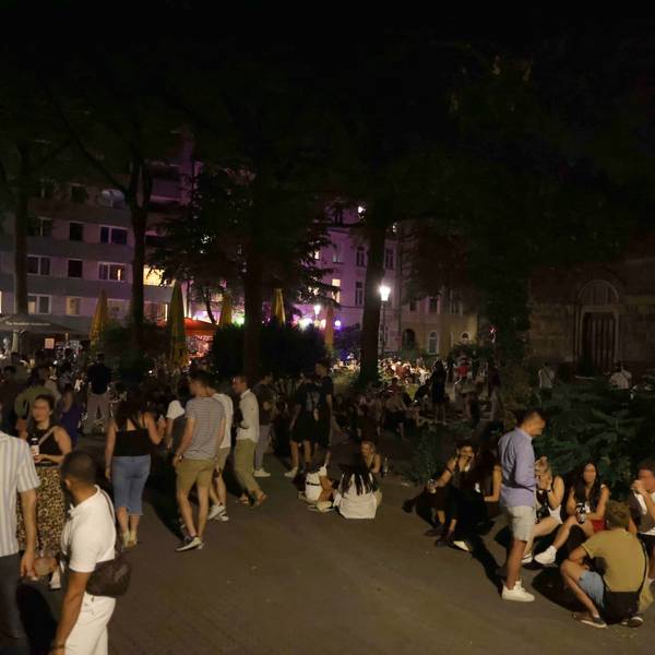 Eine große Gruppe junger Menschen sitzt auf dem Brüsseler Platz.