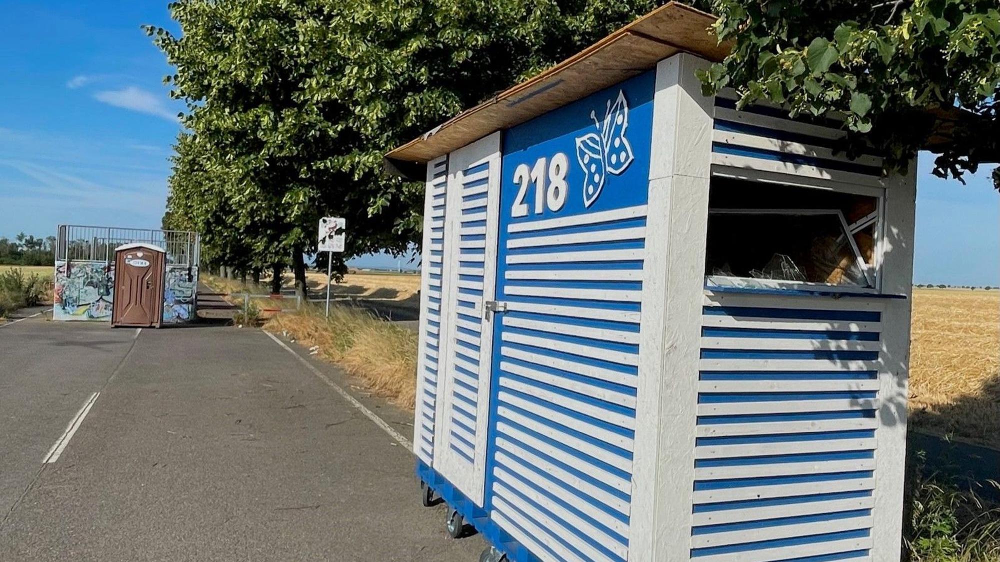 An einer Straße steht ein blau-weiß gestreiftes Häuschen.