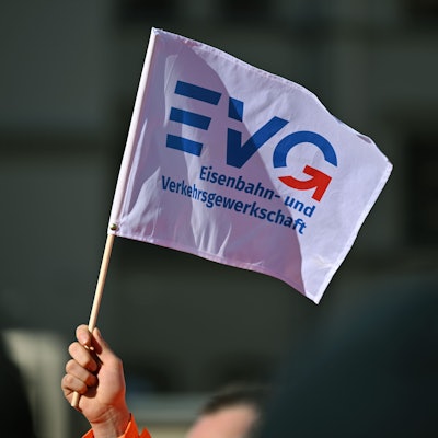 Ein Teilnehmer am Warnstreik vor dem Erfurter Hauptbahnhof schwenkt ein Fähnchen der Eisenbahn- und Verkehrsgewerkschaft (EVG).