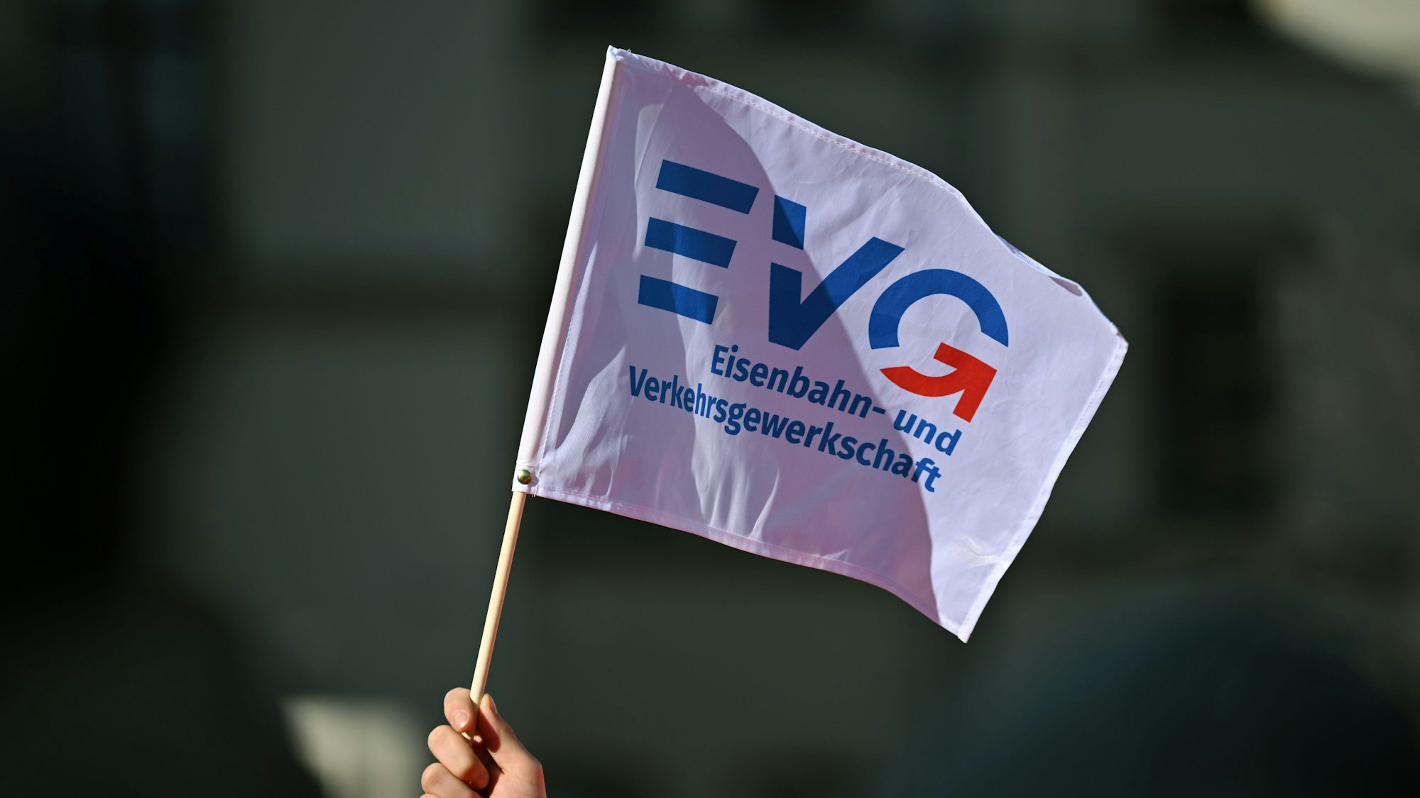 Ein Teilnehmer am Warnstreik vor dem Erfurter Hauptbahnhof schwenkt ein Fähnchen der Eisenbahn- und Verkehrsgewerkschaft (EVG).