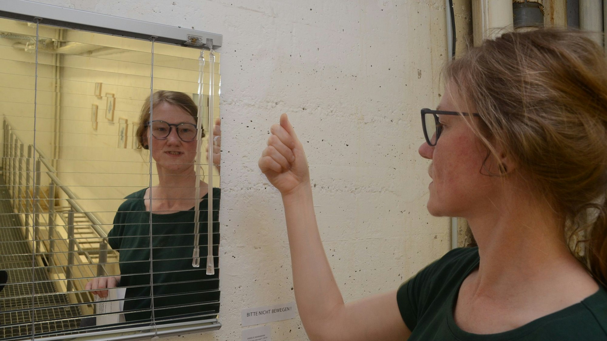 Annelie zeigt eine Jalousie, bei der sie die Lamellen durch Spiegelglas ersetzt hat.