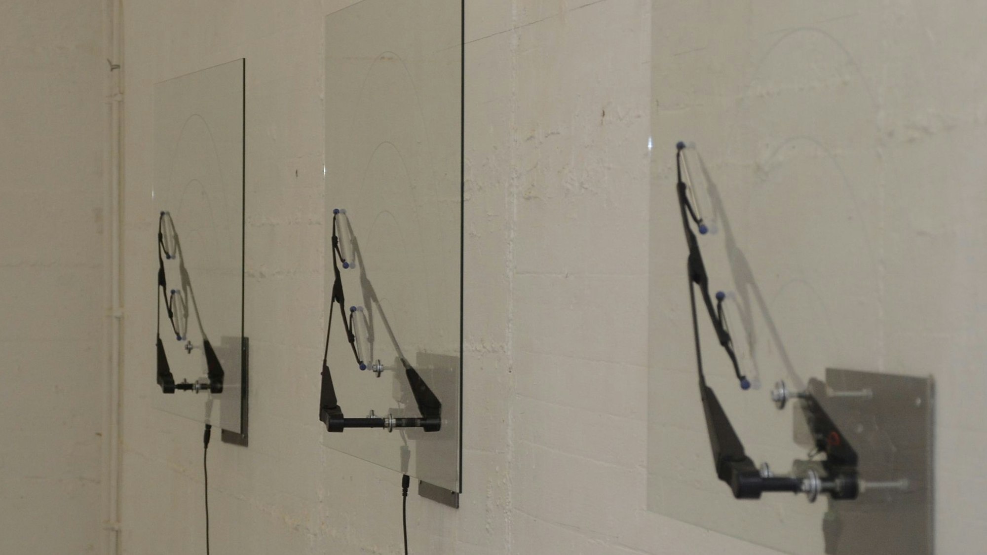 Mit lautem Kreischen kratzen Korund-Kugeln in der Installation über Glasplatten.