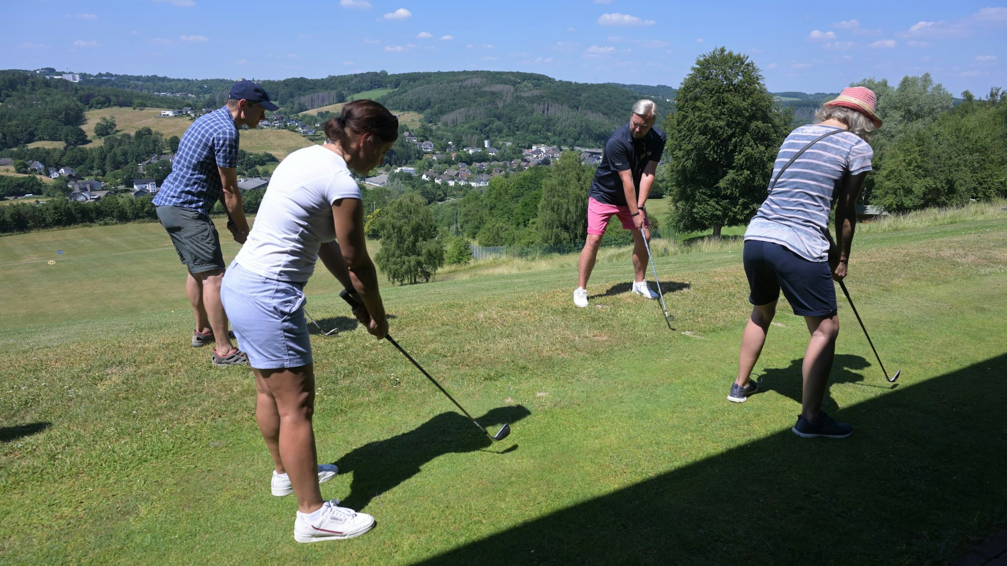 Vier Personen üben einen Golfschlag.