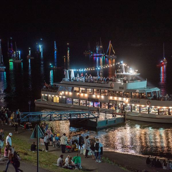 Es ist Nacht am Ufer des Rursees. Das Touristen-Schiff Stella Maris leuchtet hell auf dem Wasser.