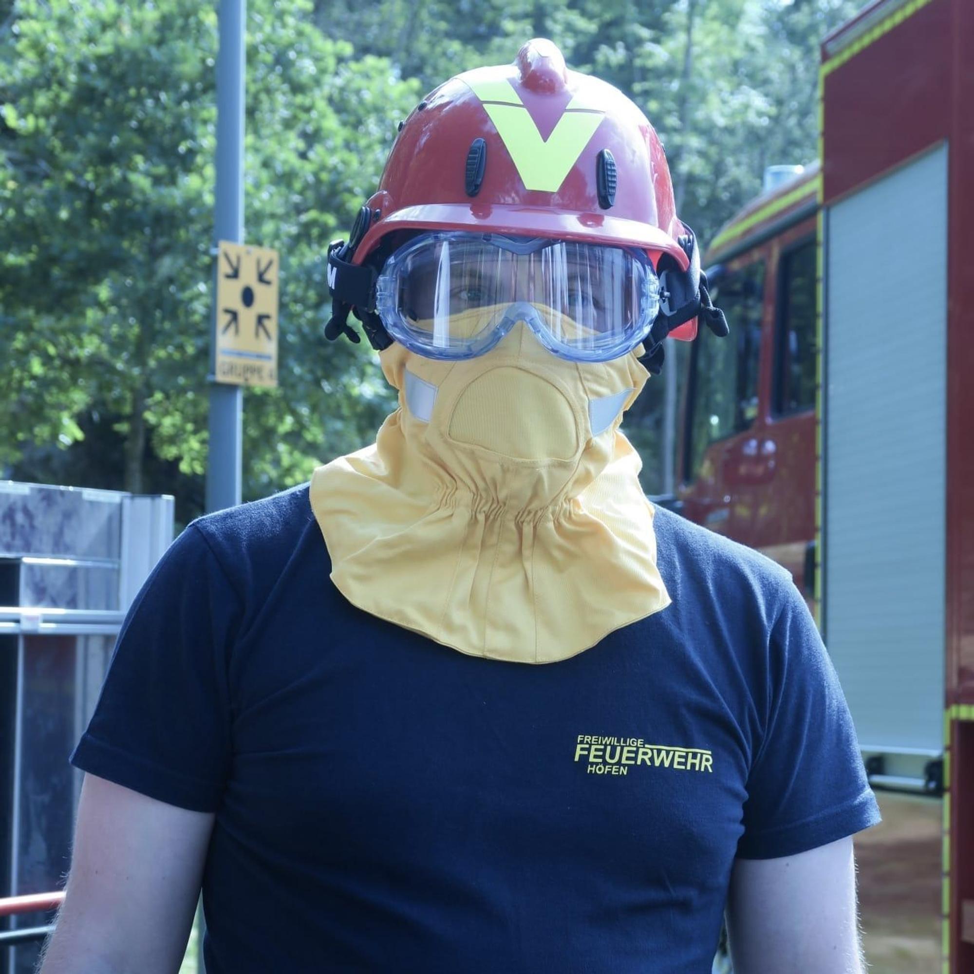 Ein Feuerwehrmann trägt die Schutzbekleidung für den Kopf.