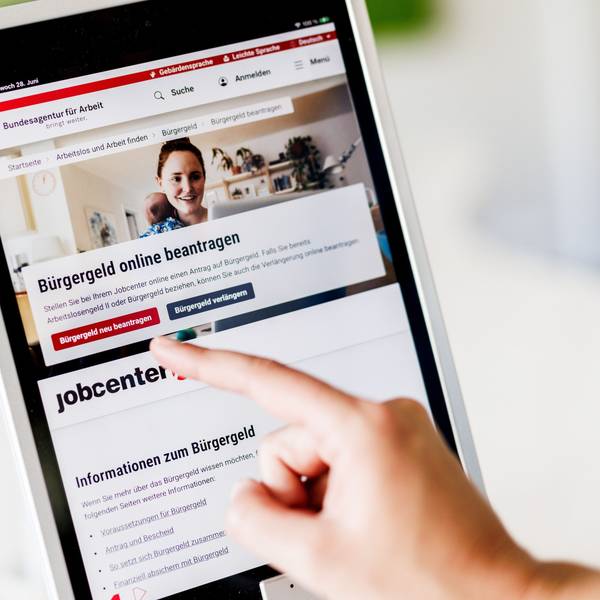 Eine Frau tippt auf einem Tablet auf einen Link zum Beantragen des Bürgergeldes im Kundenbereich im Jobcenter Berlin Mitte.