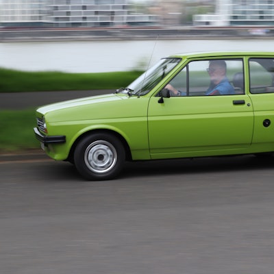Ein grüner Ford Fiesta fährt auf der Straße.