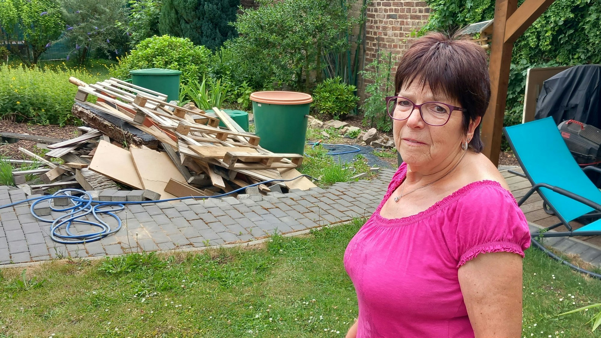 Katharina Willwerts steht in einem Garten. Hinter ihr ist ein Berg aus Holz.