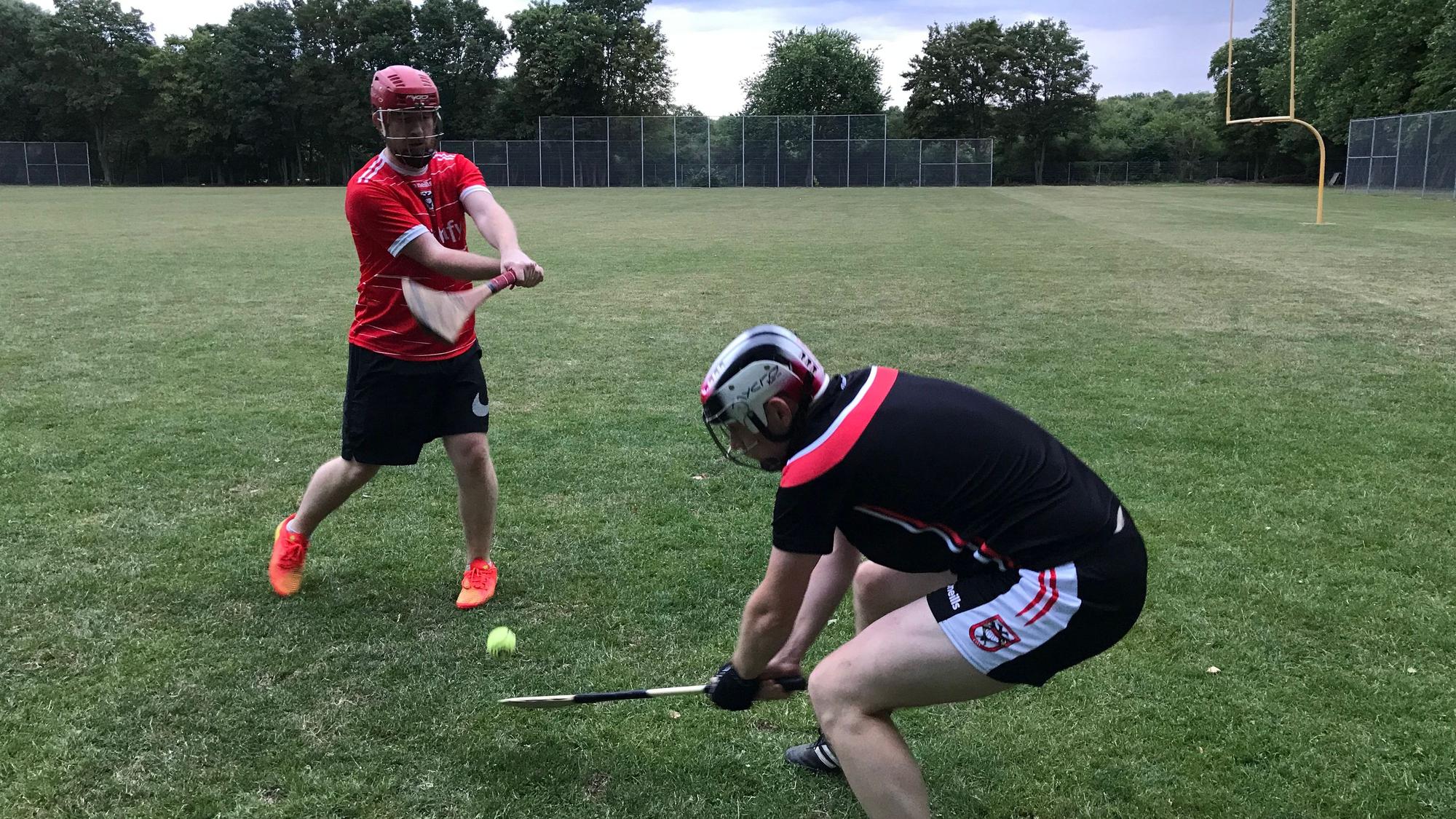 Zwei Spieler kämpfen mit ihren Hurling-Schlägern um den Ball.