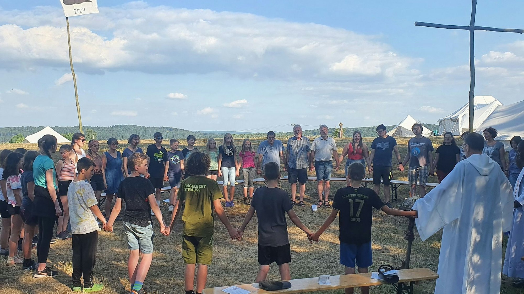 Kinder und Jugendliche halten sich bei einem Gottesdienst unter freiem Himmel an den Händen.