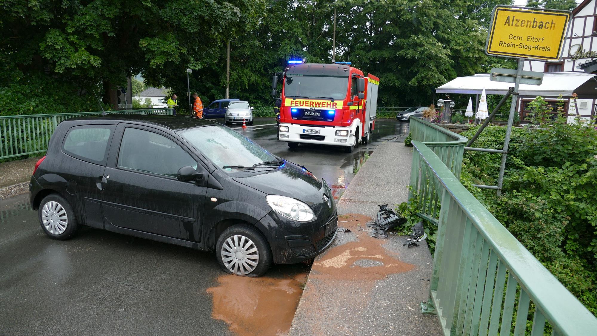 Ein Renault Twingo steht quer auf einer Brücke, vor dem Fahrzeug liegen Autoteile. Die Feuerwehr steht im HIntergrund.