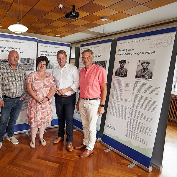 Drei Männer und eine Frau stehen vor den Stellwänden einer Ausstellung.