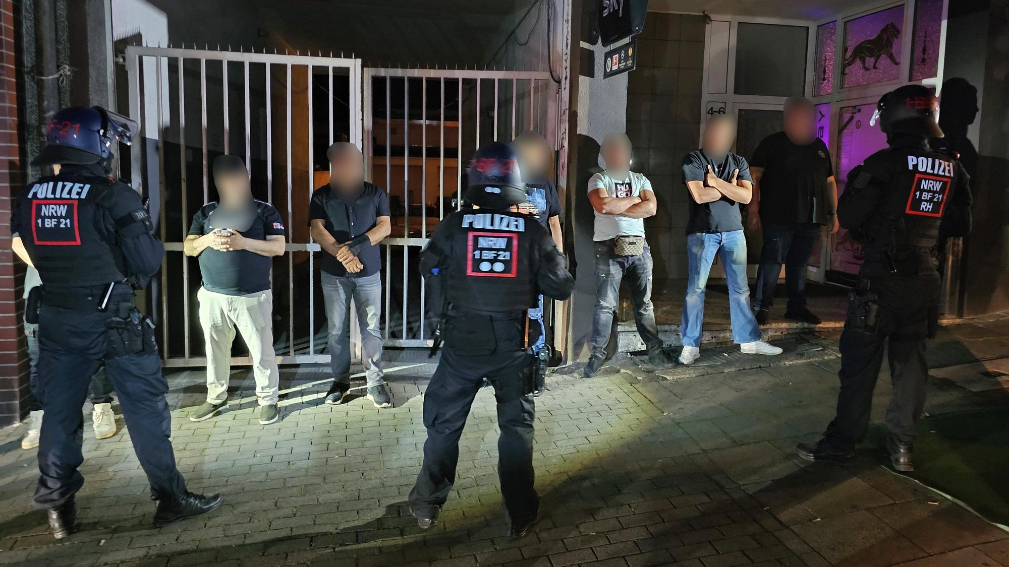 Polizisten halten einige Männer, die sich an einer Schlägerei beteiligten, in Essen fest.
