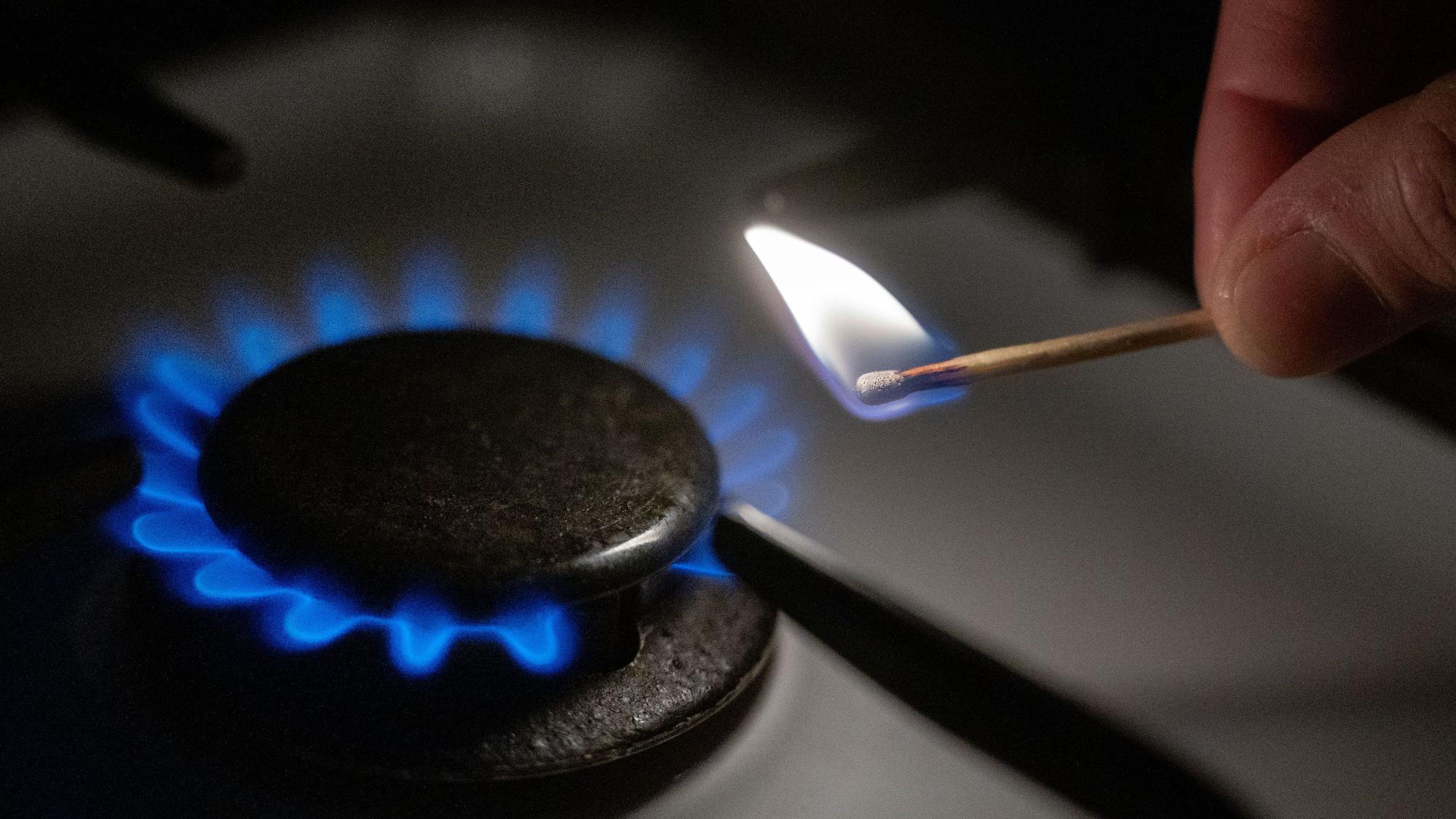 Eine Gasflamme wird auf einem Küchenherd mit einem Streichholz entzündet.