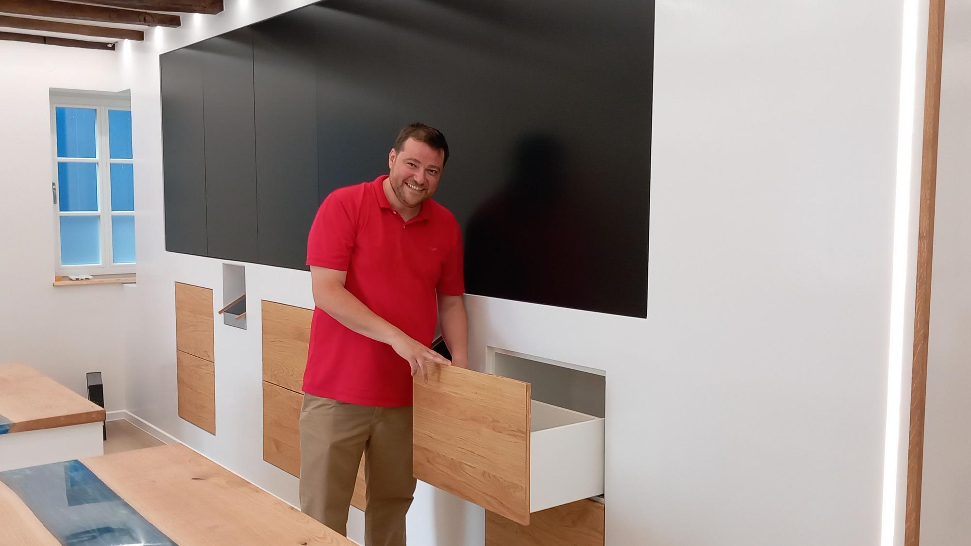 Michael Ramon Braun zeigt, wie die einst von seiner Mutter geführte Apotheke künftig aussehen wird. Schubladen gibt es nur noch unter der Wand mit Panoramabildschirmen. Dahinter arbeitet ein Kommissionierroboter.