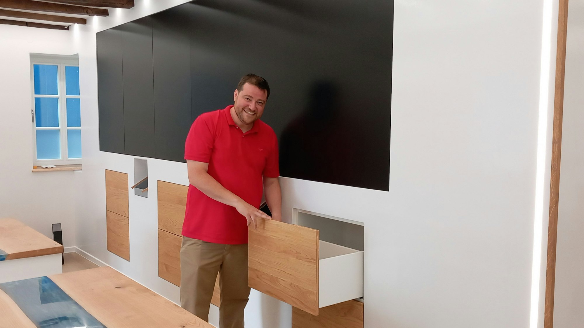 Michael Ramon Braun zeigt, wie die einst von seiner Mutter geführte Apotheke künftig aussehen wird. Schubladen gibt es nur noch unter der Wand mit Panoramabildschirmen. Dahinter arbeitet ein Kommissionierroboter.