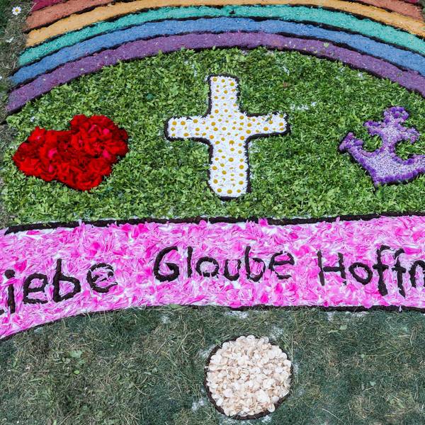 Die Wörter „Liebe, Glaube, Hoffnung“ sind zu lesen in einem Blumenteppich.