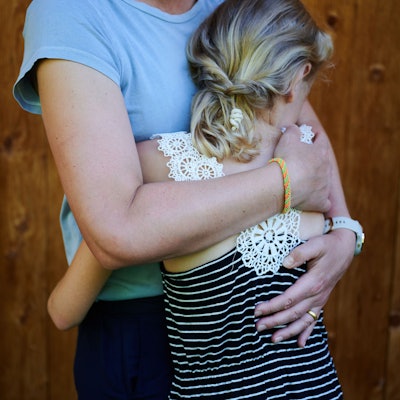 Ein Mädchen wird von seiner Mutter in den Arm genommen und getröstet.