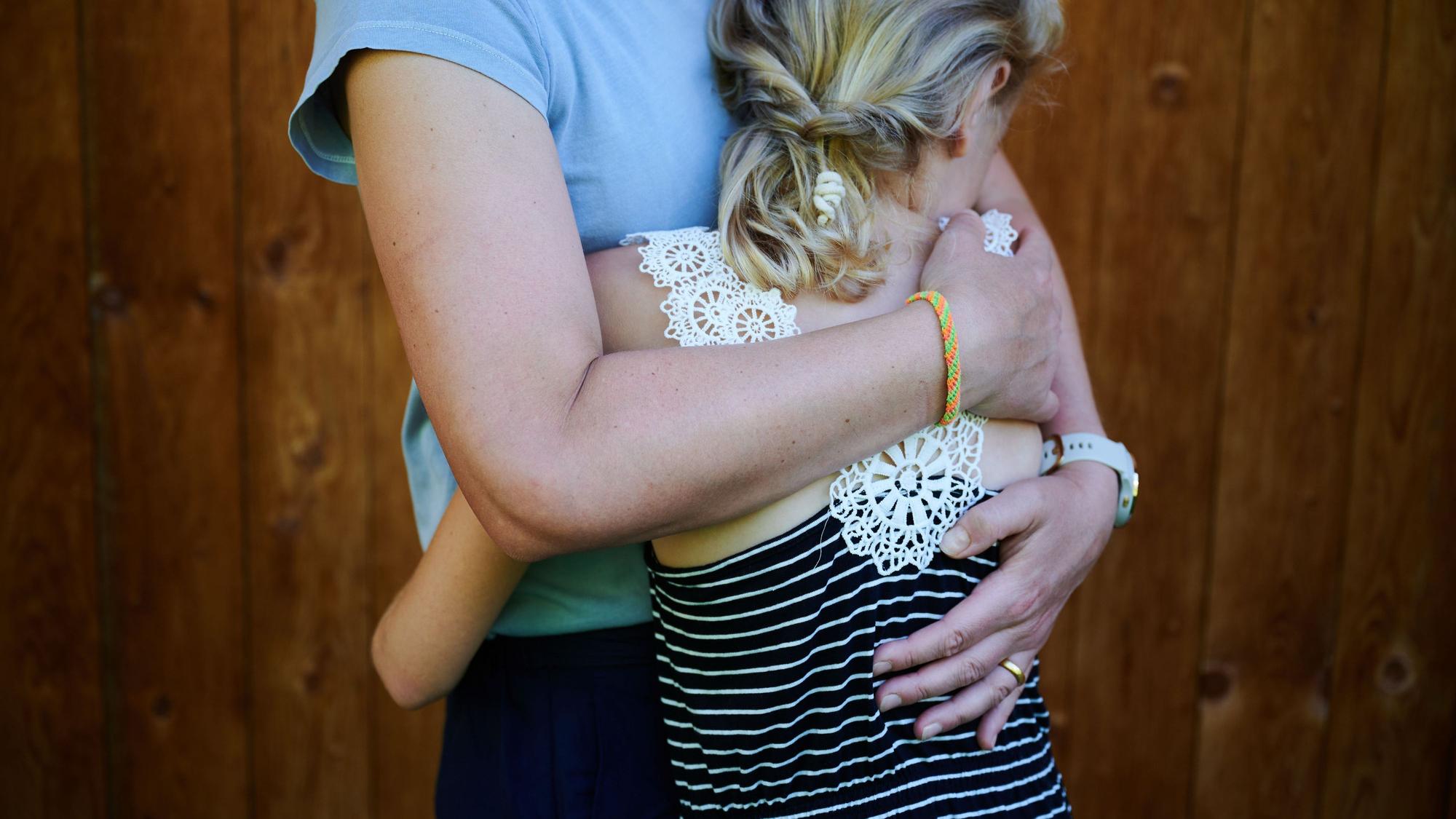 Ein Mädchen wird von seiner Mutter in den Arm genommen und getröstet.