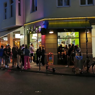 Menschen stehen vor dem Kiosk am Brüsseler Platz.