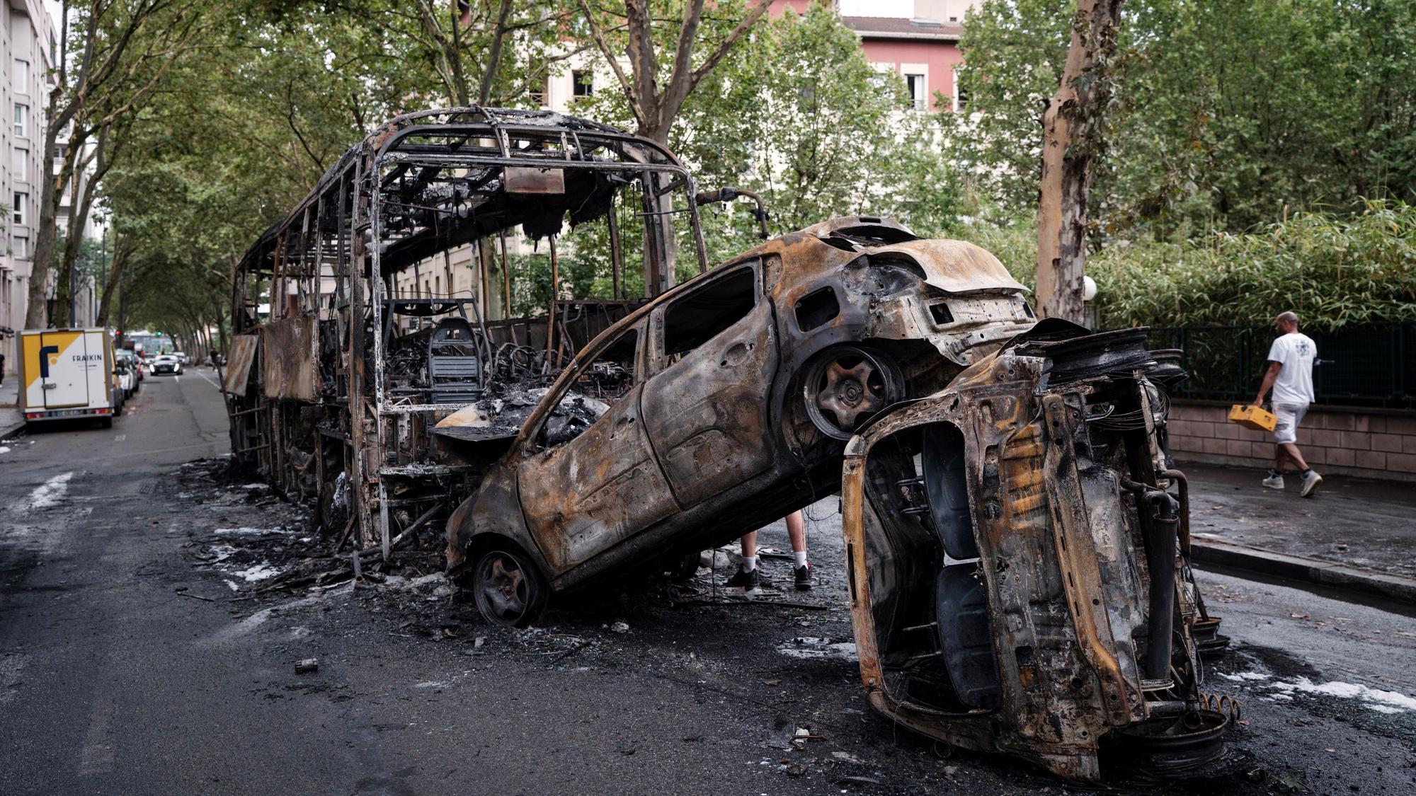 30.06.2023, Frankreich, Lyon: Ausgebrannte Autos und ein Bus stehen in einer Straße. Nach dem Tod eines Jugendlichen bei einer Polizeikontrolle gab es in mehreren französischen Großstädten heftige Krawalle. Foto: Laurent Cipriani/AP +++ dpa-Bildfunk +++