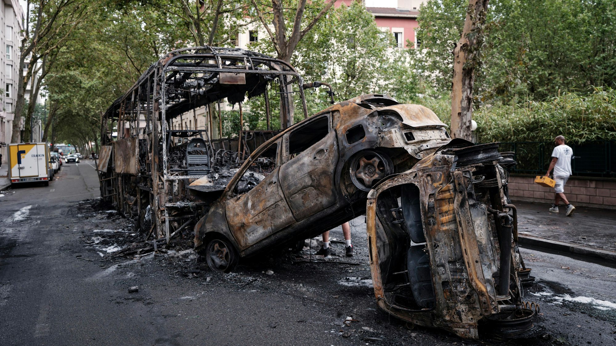 30.06.2023, Frankreich, Lyon: Ausgebrannte Autos und ein Bus stehen in einer Straße. Nach dem Tod eines Jugendlichen bei einer Polizeikontrolle gab es in mehreren französischen Großstädten heftige Krawalle. Foto: Laurent Cipriani/AP +++ dpa-Bildfunk +++