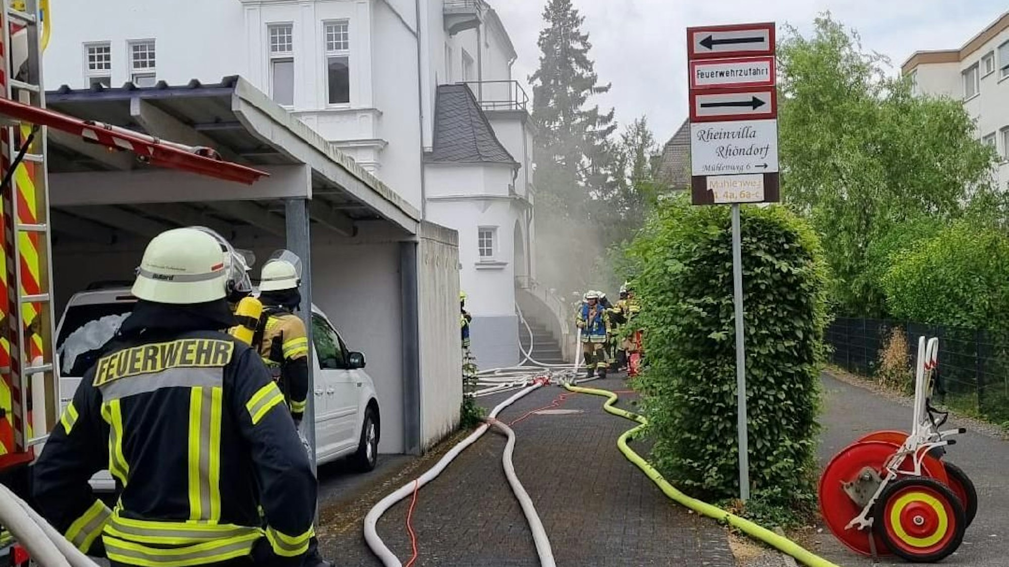 Feuerwehrleute stehen vor einem brennenden Haus.