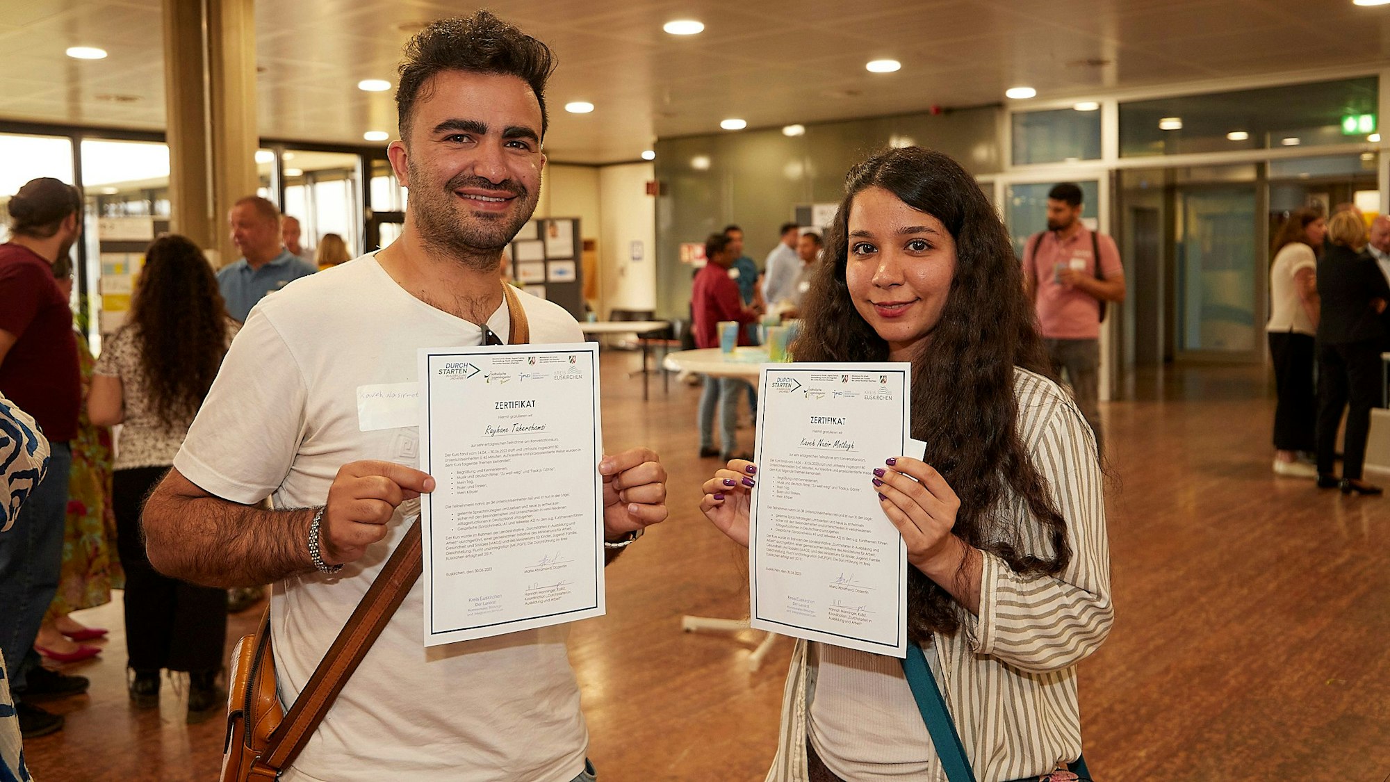 Die beiden Absolventen zeigen bei der Abschlussveranstaltung im Euskirchener Kreishaus ihre Zertifikate.