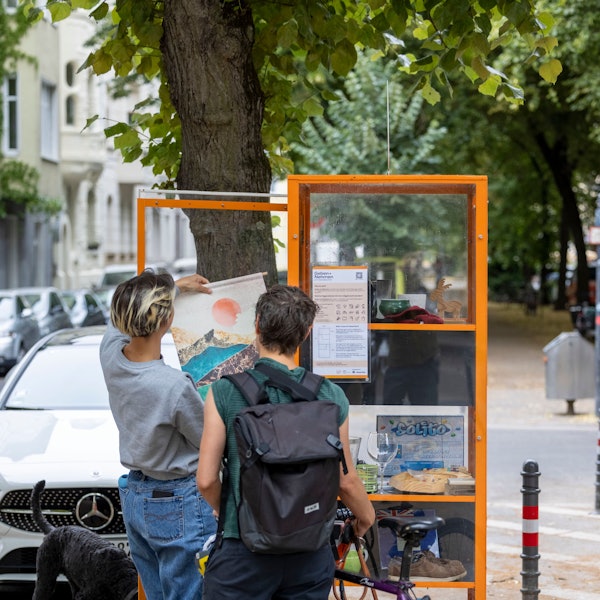 Zwei Frauen betrachten den Inhalt des Tauschregals.