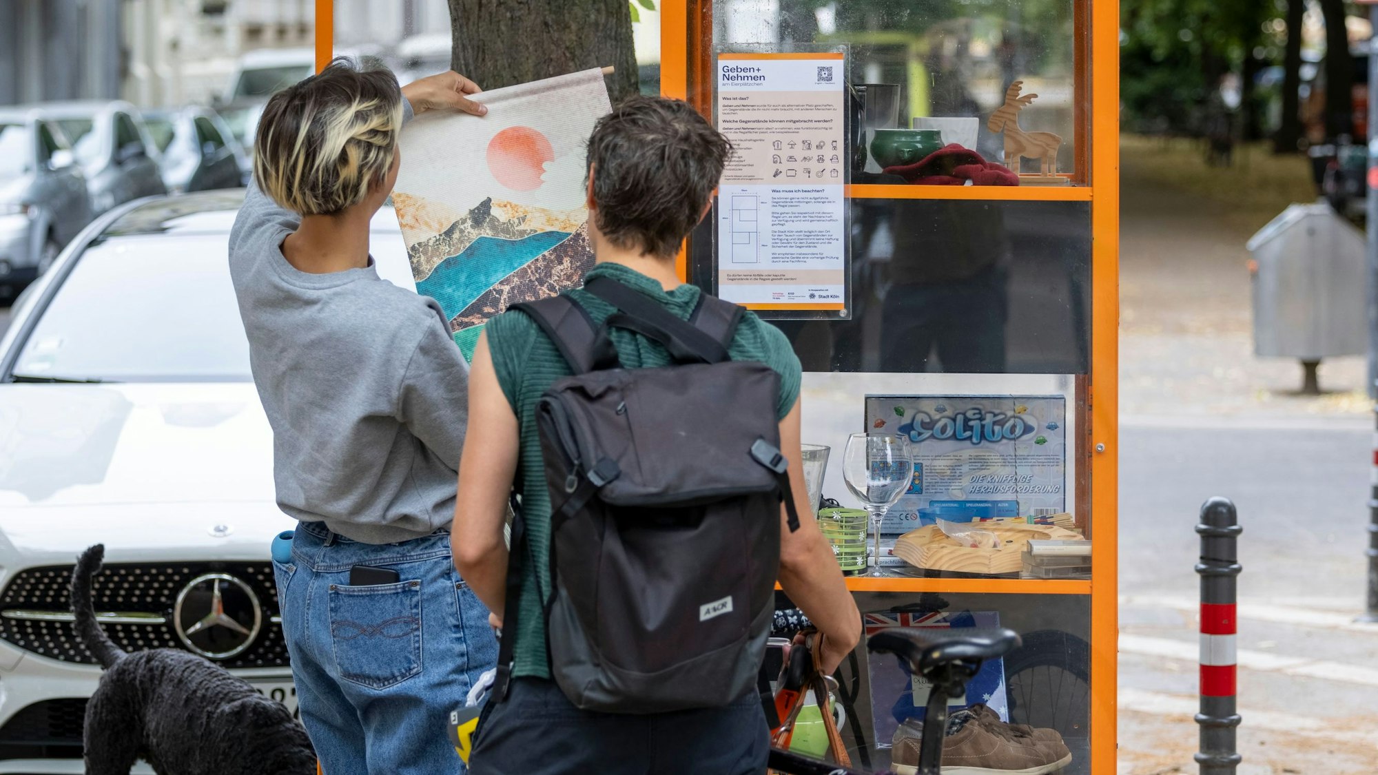 Zwei Frauen schauen sich Gegenstände am Tauschregal an.
