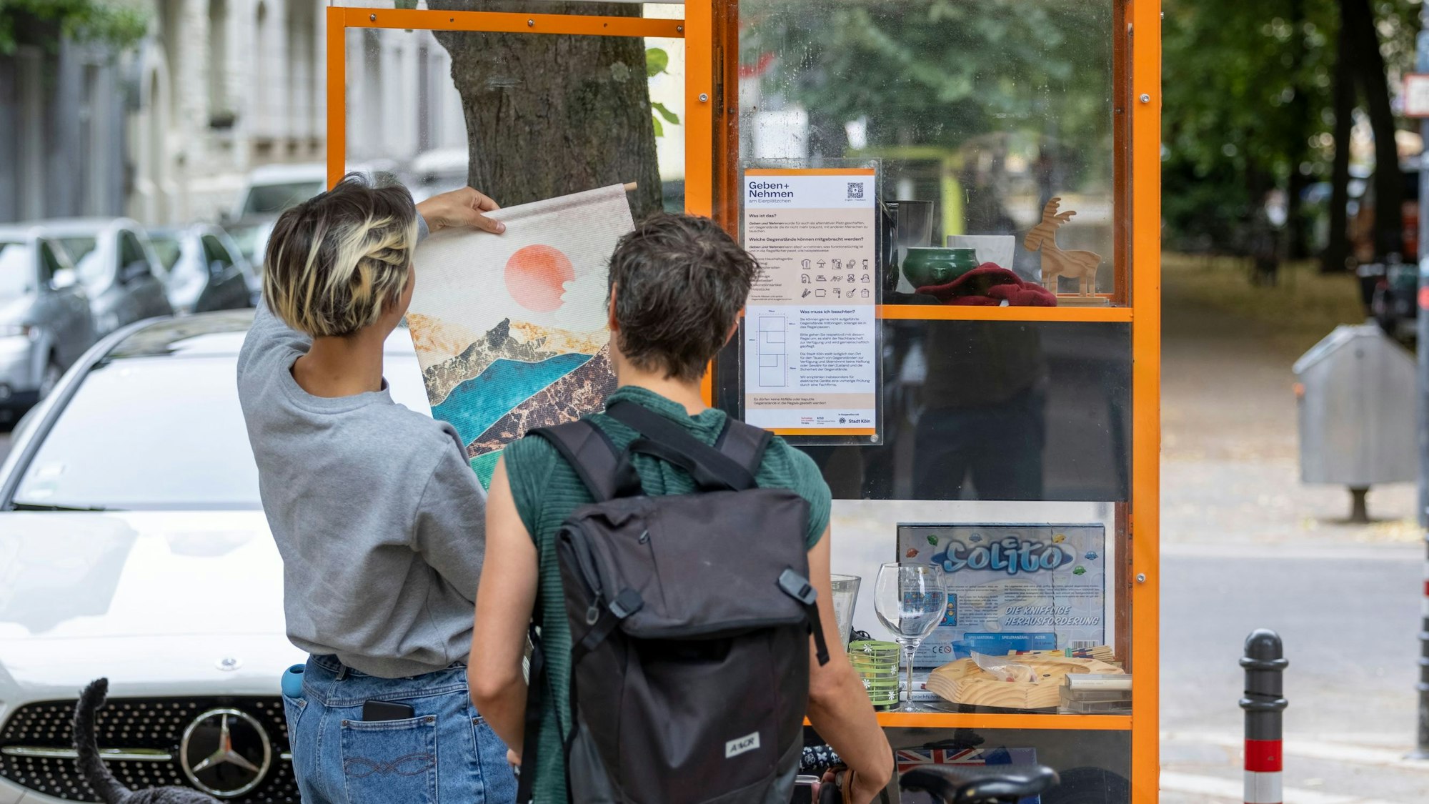 Zwei Frauen betrachten den Inhalt des Tauschregals.