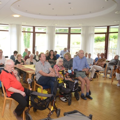 Senioren sitzen auf Stühlen.