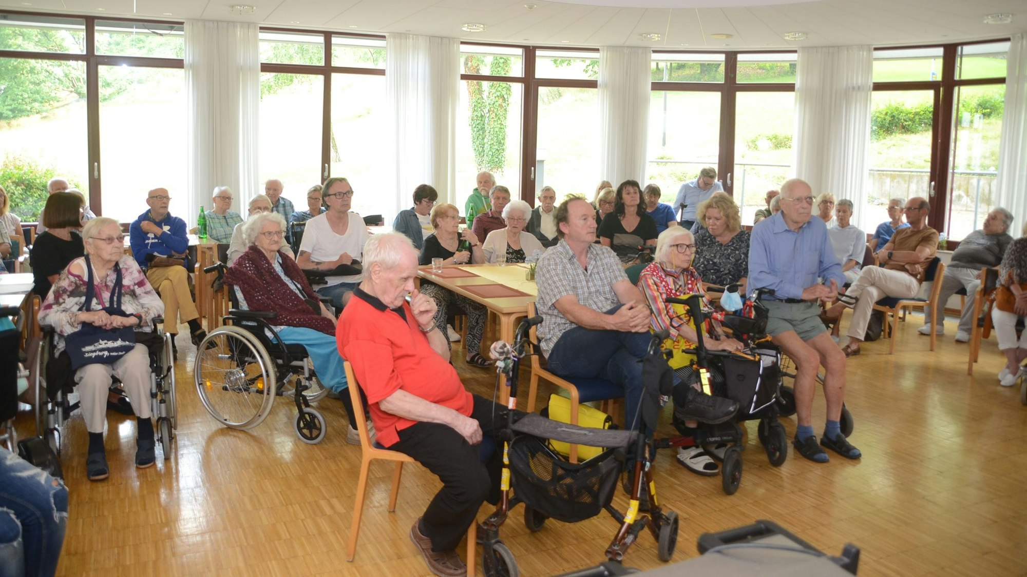 Senioren sitzen auf Stühlen.