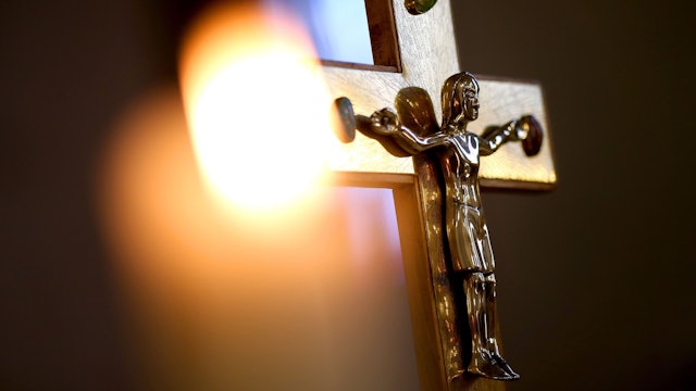 Ein Jesuskreuz und eine brennende Kerze in einer Kirche.