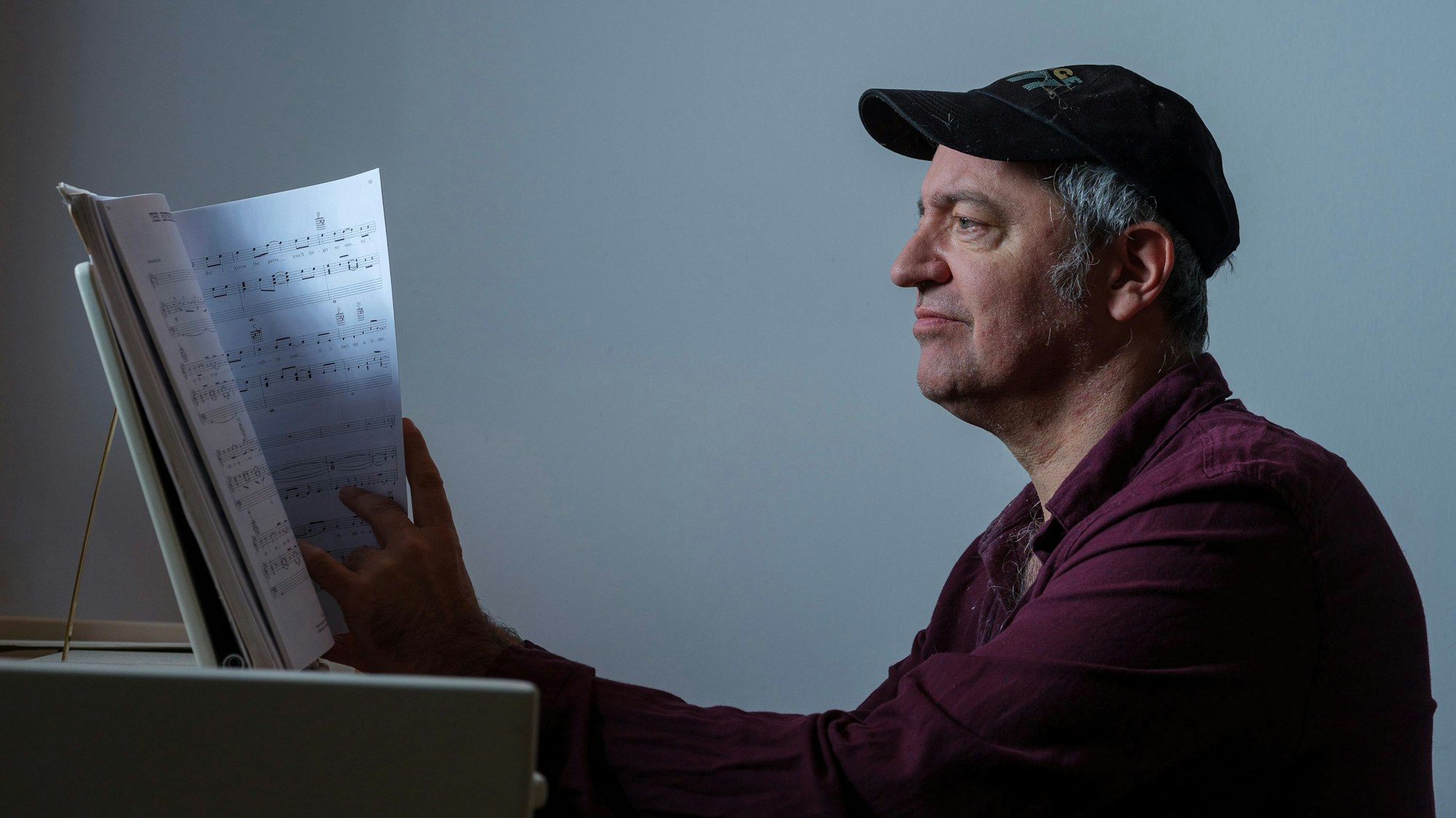 Rainald Grebe sitzt an einem Klavier und liest Noten