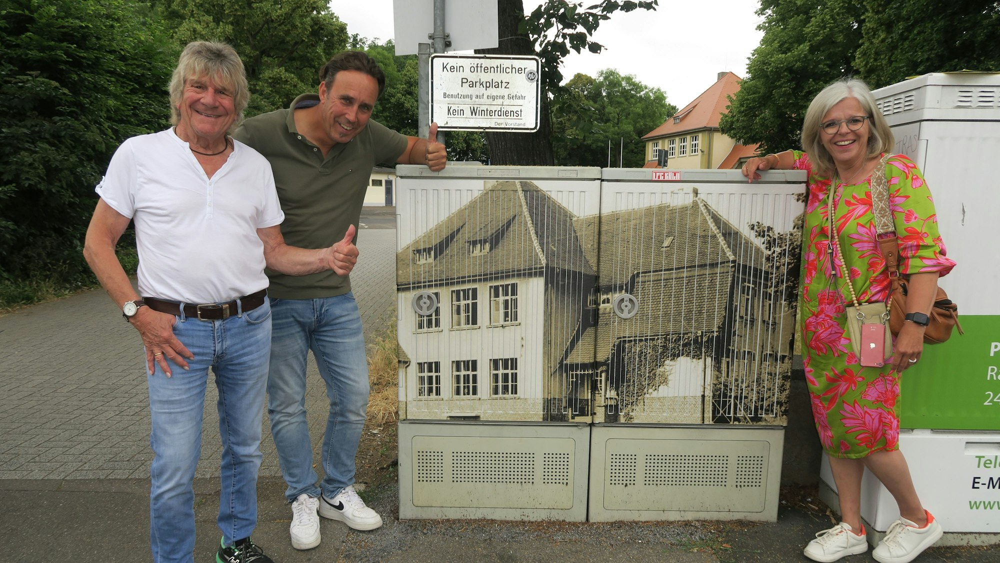 Zwei Männer und eine Frau stehen an einem Stromkasten.