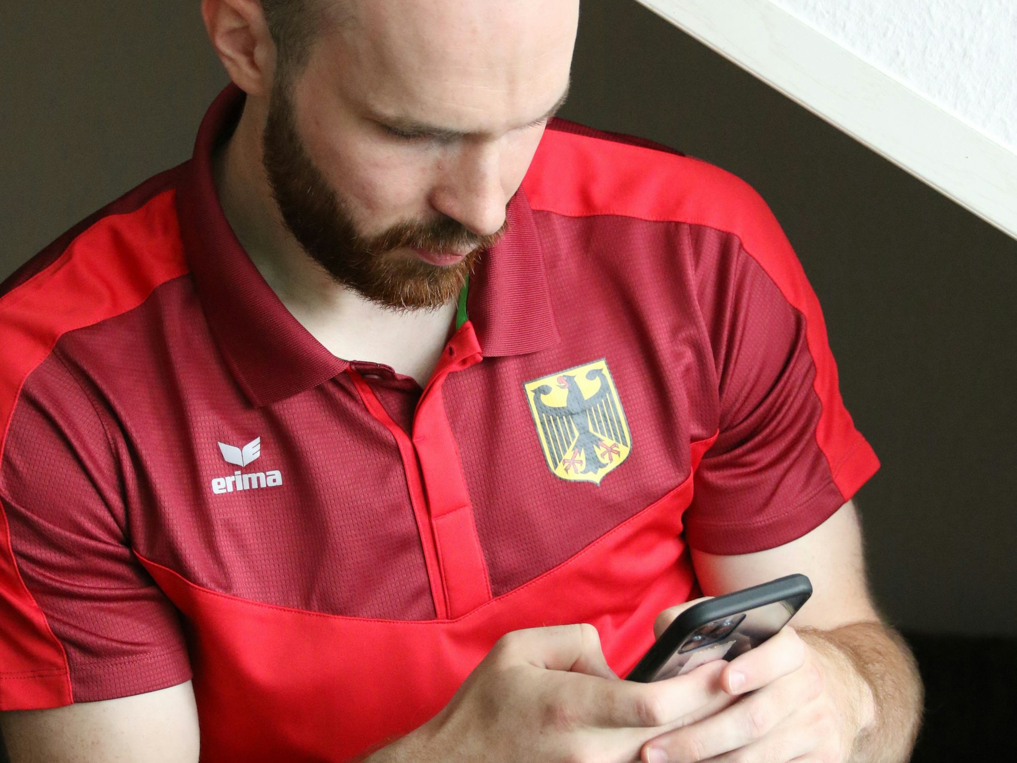 Gehörlosen-Handball-Nationalspieler Simon Schöller blickt auf sein Handy.